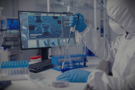 Virolog coducting experiment in the course of coronavirus pandemic with micropipette. Chemist in modern laboratory doing research using dispenser during global epidemic with covid-19.